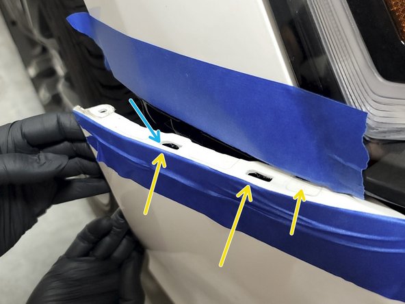 Use a forceful but controlled motion with both hands to pop the bumper out of the three fender clips as shown