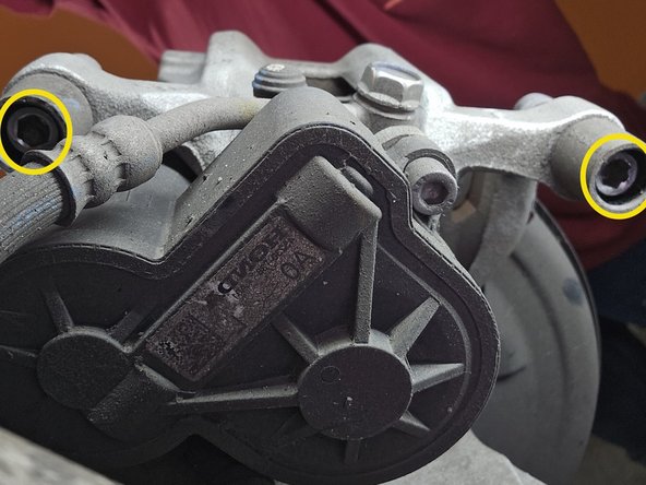 Using a 7mm Allen head socket and a 3/8" ratchet, reinstall the caliper slider bolts as shown and torque to 25 Ft/Lbs