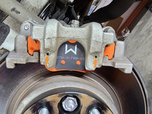 Using both hands, insert the tension clip ends into the mounting holes on the caliper as shown