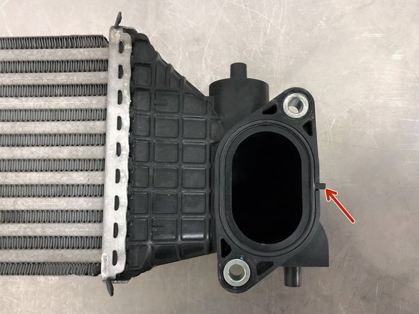 Remove the OEM O-ring from the cold side endtank of the OEM intercooler by pulling it free using the small tab shown with the red arrow