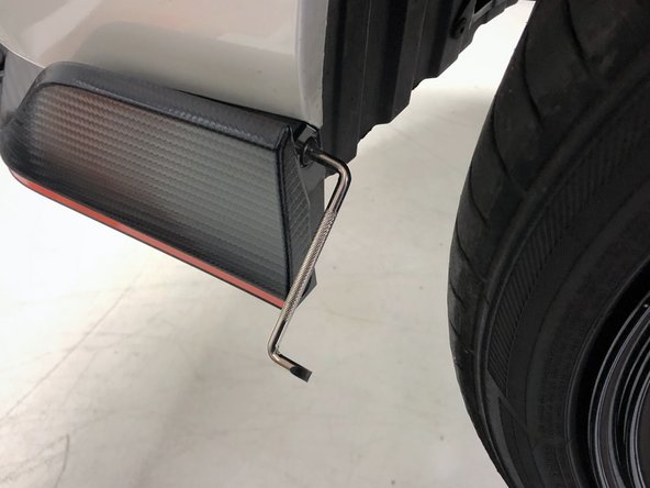 Look into the driver's side fender, in front of the front tire. Remove the four phillips head screws that attach the bumper to the fender liner