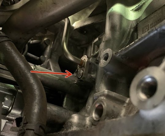 Remove the10mm bolt holding the hard oil feed line as shown