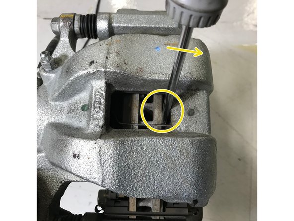 With the bolts removed, slide the brake caliper off the rotor in the direction of the orange arrow