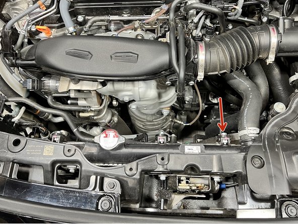Locate the 10mm bolt next to the radiator hose as shown and remove it