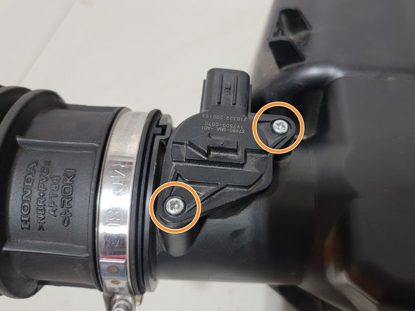 Using a small Phillips screwdriver, remove both screws securing MAF sensor to OE Airbox Lid