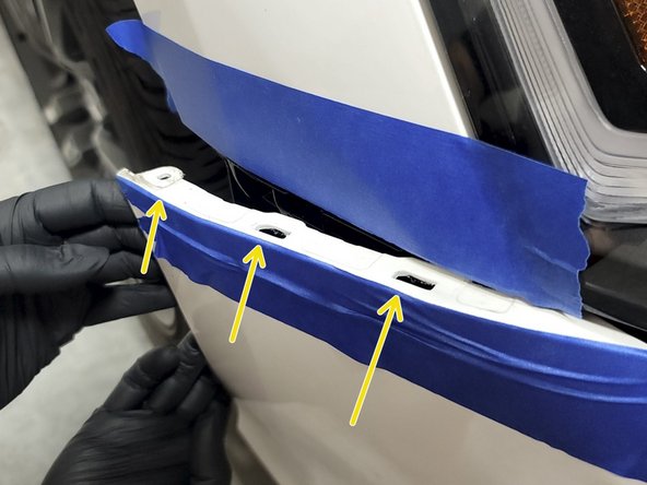 Use a forceful but controlled motion with both hands to pop the bumper out of the three fender clips as shown