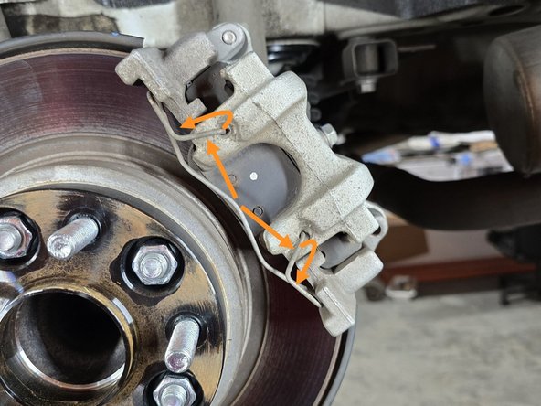 Using a flat head screw driver, pop the tension clip out of its retaining holes as shown