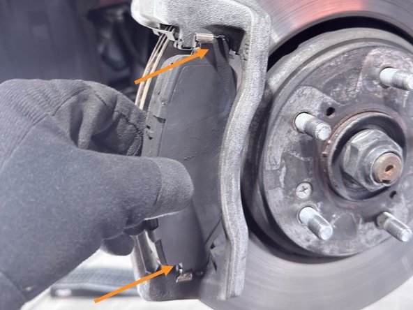Install the outer brake pad into the caliper bracket by aligning the top and bottom edges and pushing at an angle as shown