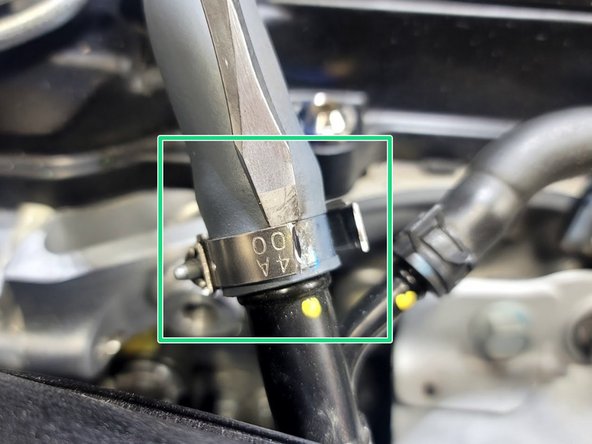 Partially cut through band of clamp. The idea is to remove enough material that the clamp will break but not so much to cut into the rubber