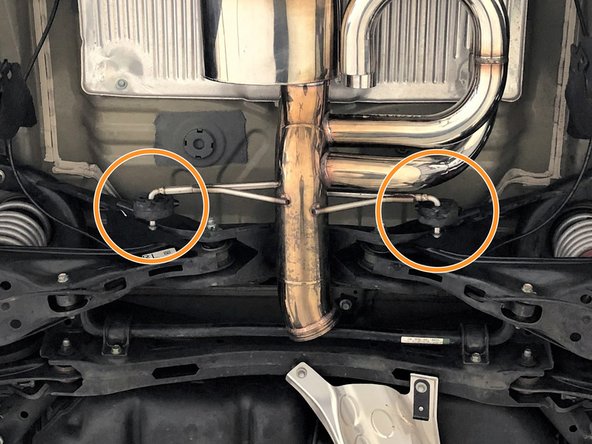 While supporting the rear of the muffler section, insert both forward hangers as shown