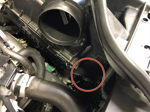 Once clear from the battery cables, reach your hand under the airbox to align the rubber grommet on the metal peg shown in the previous step (second image)