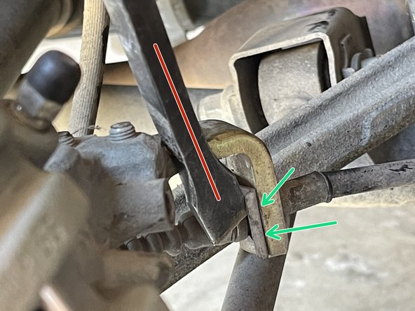 Using  a small pry bar, remove the metal clip securing the parking brake cable to the metal bracket