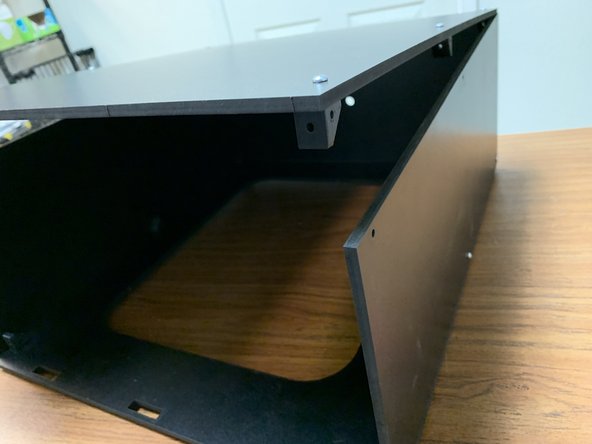 Orient the top panel assembly so the holes on the sides of the brackets line up with the holes at the top of your side and rear panels.