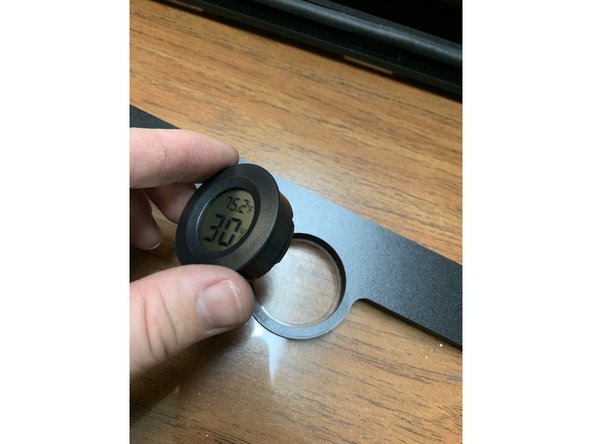 GENTLY press in the hygrometer into the acrylic lid/faceplate assembly as shown.