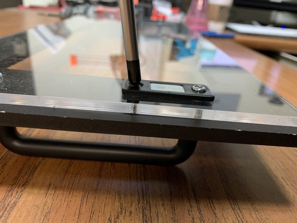 Using two of the remaining M3 x 6mm wood screws, one on each of the left and right sides of the lid, fasten the Magnet Catches.  The screw goes from the interior through the Mag Catch and Acrylic Lid, and bites into the Faceplate as shown.  Do not overtighten, or you will risk stripping the Faceplate material.