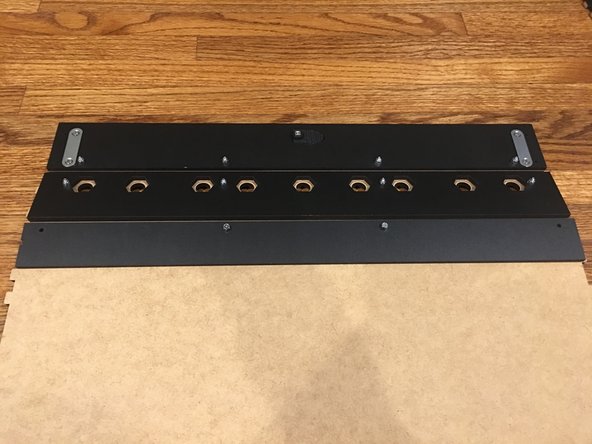 Flip the Base panel over to where the unfinished side is  facing up, being careful to keep the 2 inserted bolts and Steel support beam in place underneath. There should be enough bolt sticking up through the top of the Base panel to complete this step.