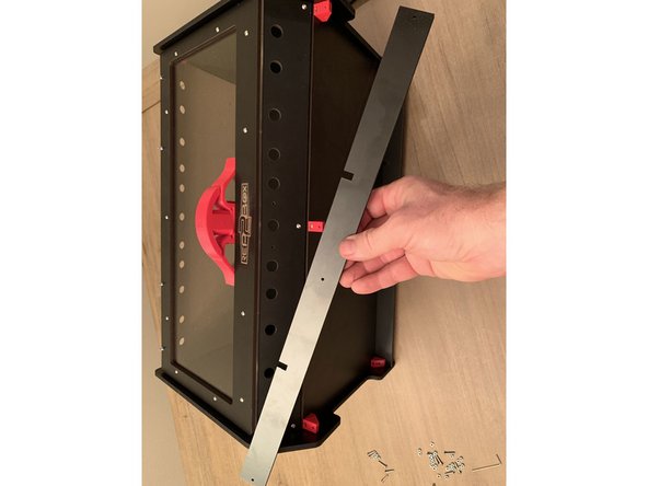 LOOSELY Screw the base reinforcement bar in place on the front 3 brackets on the base panel as pictured. Just enough to hold it in place.