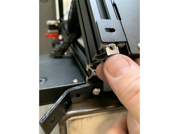 Remove one of the remaining screws holding the angle bracket to the other extrusion so you can tip the angle bracket down and add a slide nut to the bottom side of the base side extrusions as shown.
