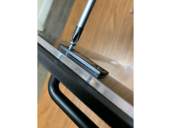 Using two of the remaining M3 x 6mm wood screws, one on each of the left and right sides of the lid, fasten the Magnet Catches.  The screw goes from the interior through the Mag Catch and Acrylic Lid, and bites into the Faceplate as shown.  Do not overtighten, or you will risk stripping the Faceplate material.