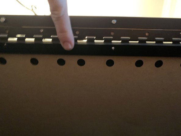 The screw at the top center should be recessed and have its head resting atop the metal hinge. If there is still a knockout piece in the top panel preventing this remove it now. The front center hole in the top panel needs to be large enough for the screw head to pass through completely.