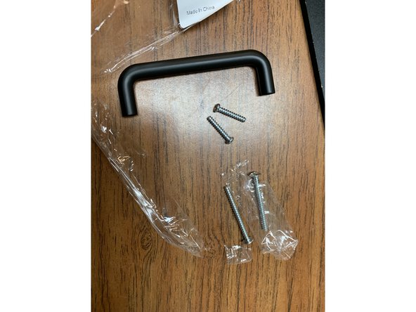 Locate the two Lid Handles (Part 13) and open up the included screws. Discard both of the LONGER screws.  They will not be needed.