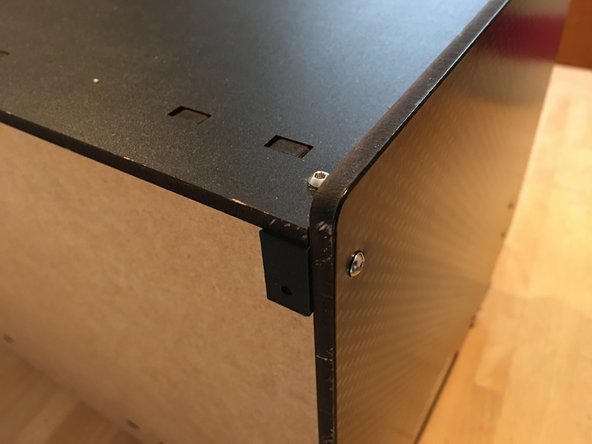 DESKTOP KIT: Press square nuts into one end and the center holes of your remaining universal brackets. Fasten these brackets to the rear corners of the top plate and the top rear corner of the side panels using 16mm bolts. The flat edge of the U Bracket should be facing AWAY from the back of the box as is in the picture.