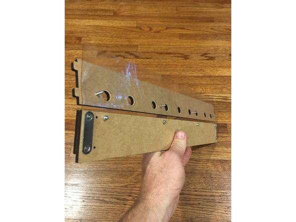 With everything face down (logo  down), place the Outer Exit Plate (the one WITH tabs) under the vinyl sheet as pictured.