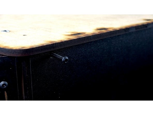 SEAL KIT ONLY: Use a 20mm bolt to secure the 3D Printed Trapezoidal Corner Bracket on the side panel to the top panel. You should have an open holes on the ends of the top panel towards the front. The 20mm bolt will pass through the top panel, the vinyl, the clamp panel, and go down in to the bracket, catching on the square nut.