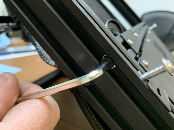 Temporarily remove the screw holding the lower crossmember beneath the belt to the side frame so we can slide the security bracket slide nut past.
