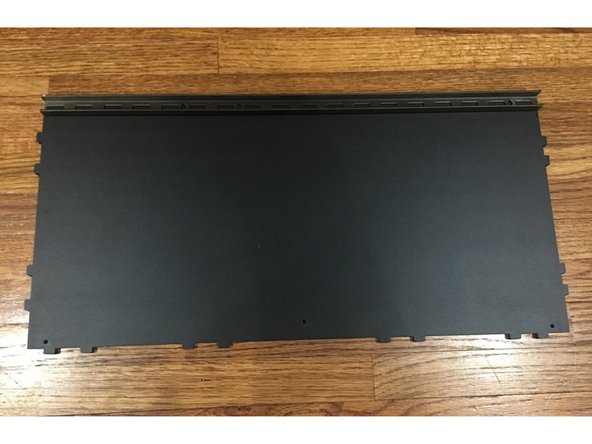 Take the Base Panel and lay it flat on the table with the finished side UP. Place the Steel support beam along the edge of the Base panel that does NOT have any tabs.
