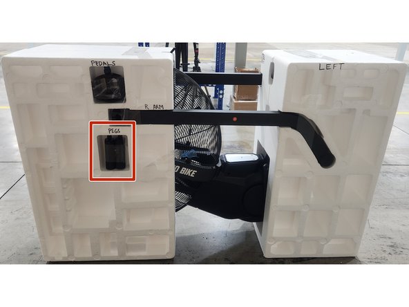 Place the foot pegs into the left side of the clamshell in the spot shown in the picture.  Secure using a piece of packing tape.