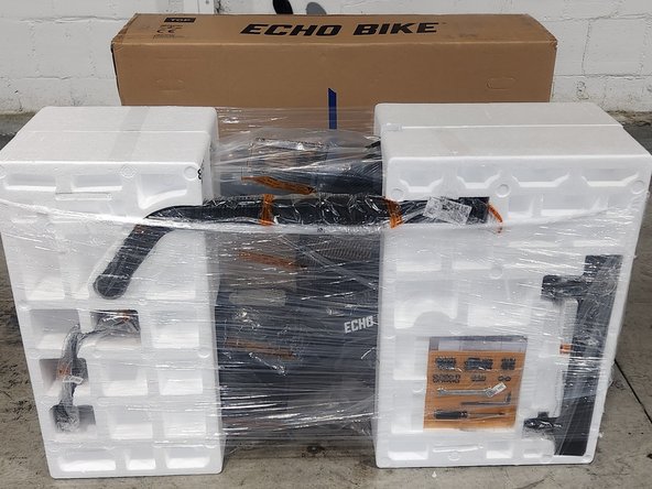 Lift straight up on the box and set it to the side.  DO NOT discard the box.  The bike chassis should be upright and encased in 2 foam clamshells.