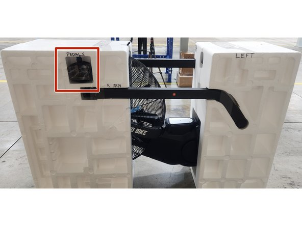Place the pedals into the left side of the clamshell in the spot shown in the picture.  Secure using a piece of packing tape.