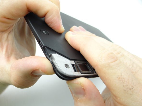 Pictures 1 &amp; 2: Using your thumbs, apply pressure to the rear case in the corner near the power button to begin separating the display assembly from the rear case.