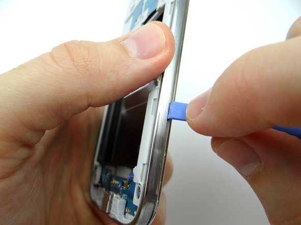 Picture 3: After you create enough separation, wedge the Blue Pry Tool between mid-frame and front panel.  Move the Blue Pry Tool up the right side and around each edge of the phone, popping the clips holding the mid-frame to the front panel along the way.