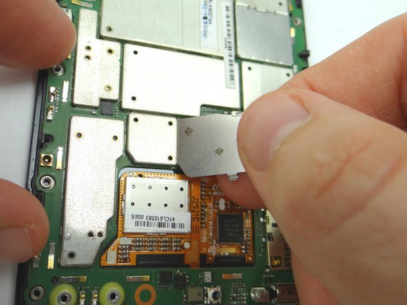 Remove the metal shield covering the display ribbon connectors: Use your fingernail to push down to free tab '1' first.  Then pull left to free tabs '2' and '3'. Place in COMPARTMENT F.