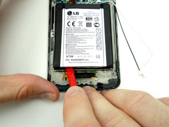 Use the flat end of the spudger to work your way through the adhesive.