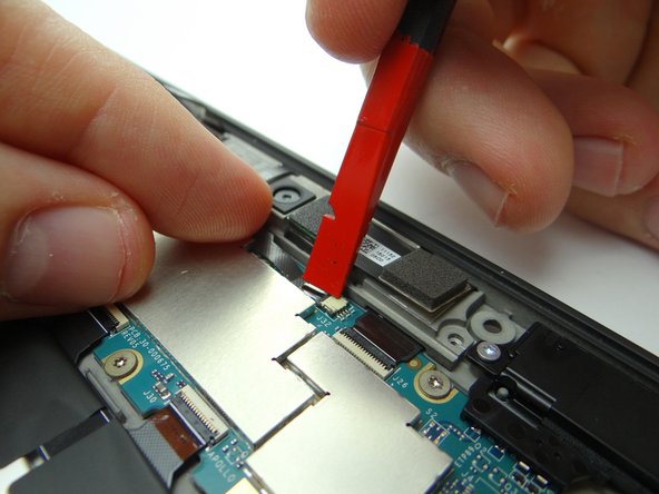 Hold the cable in place with your pointer finger while closing the ZIF connector using the flat end of the spudger.