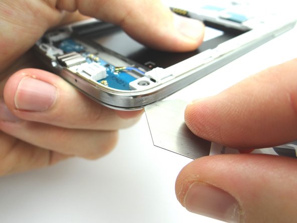 Picture 2: Use the iSesamo to create enough separation between the mid-frame and the front panel assembly to wedge a Blue Pry Tool between the two.