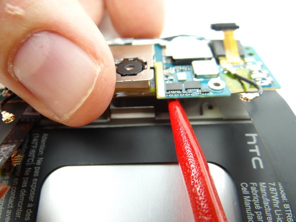 Picture 3: While lifting the right side of the daughter board with the spudger, pull the rear camera up from its socket with your thumb.