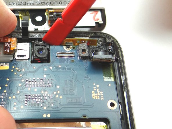 Picture 2: Place the Black Spudger to the right of the front-facing camera and pry the logic board up slightly.