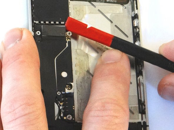 Picture 1: Place flat end of spudger under upper-right corner of the charging port assembly cable. Gently twist your hand clockwise releasing the cable from its socket on the logic board.