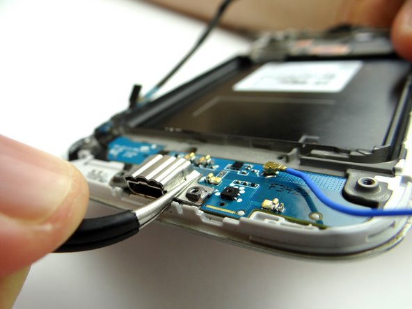 Picture 1: Use the Curved Tip Tweezers to remove the metal plate covering the charging port. You will have to apply a fair amount of force to free the plate. Place it in SLOT 3.