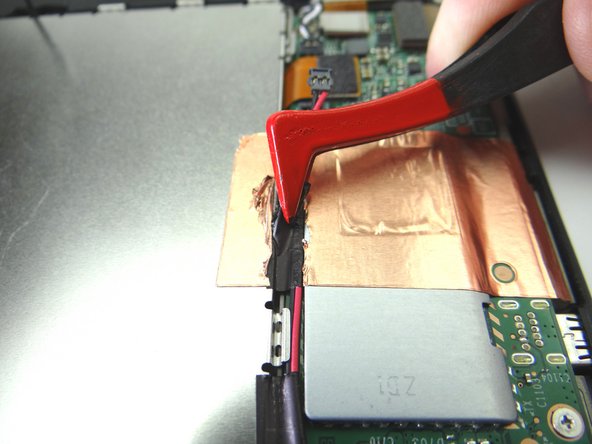 Picture 2: Use plastic tweezers to peel up the black electrical tape covering the speaker cable, without removing it, to free the cable.