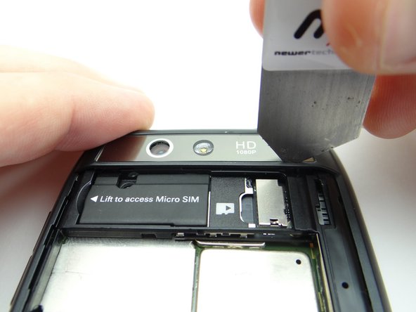 Pictures 2 &amp; 3: Wedge the iSesamo between the camera trim and rear frame in the lower-left corner.  Carefully work your way under the right side of the trim.
