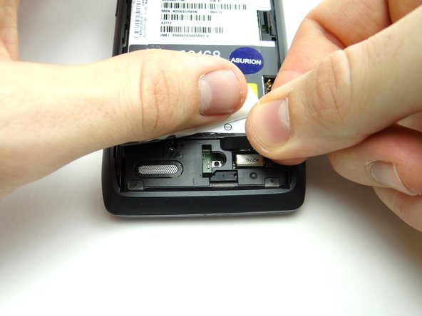 Pictures 2 &amp; 3: Use the flat end of the spudger to pry up the cover just below the '- +' signs on the battery.  Finish removing cover with your fingers and place in SLOT 1.