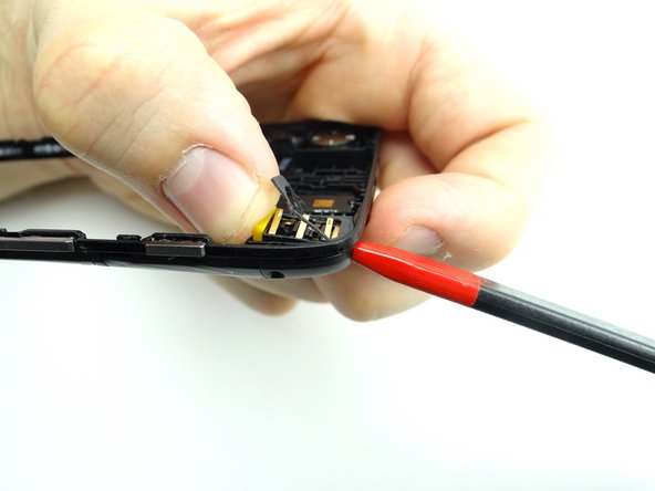 Use the pointed end of the spudger to wiggle the headphone jack and yellow spacer out of their socket.
