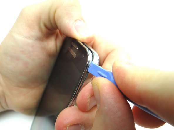 Turn the phone face up and insert the blue pry tool in the upper-right corner.