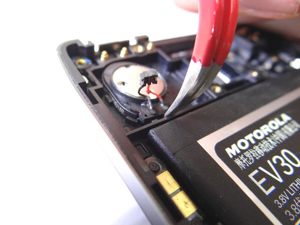 Wedge the curved-tip tweezers in the closed position under the speaker. Pry up to free it.