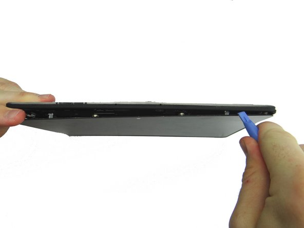 Picture 1: Hold the corner open with your finger while using the blue pry tool to release the clips along the top of the display assembly.